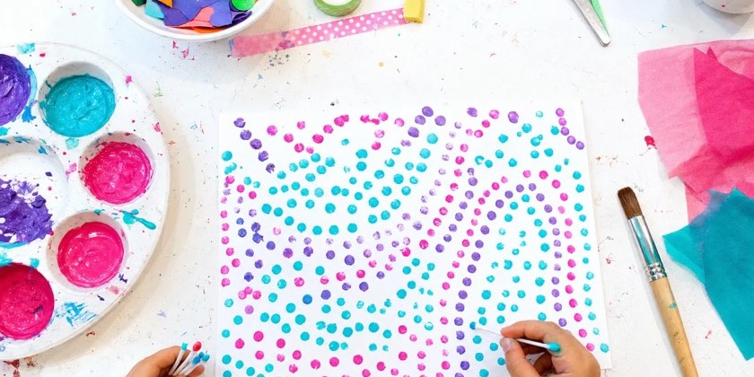 Hands dotting a page with pink, purple and teal paint