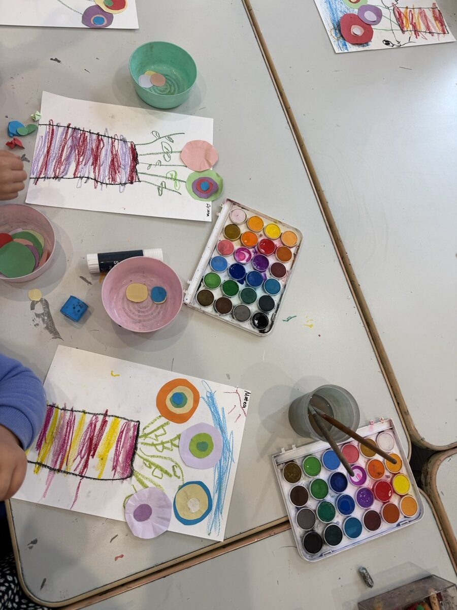 Watercolour palettes, brushes and children's work laid out on the table