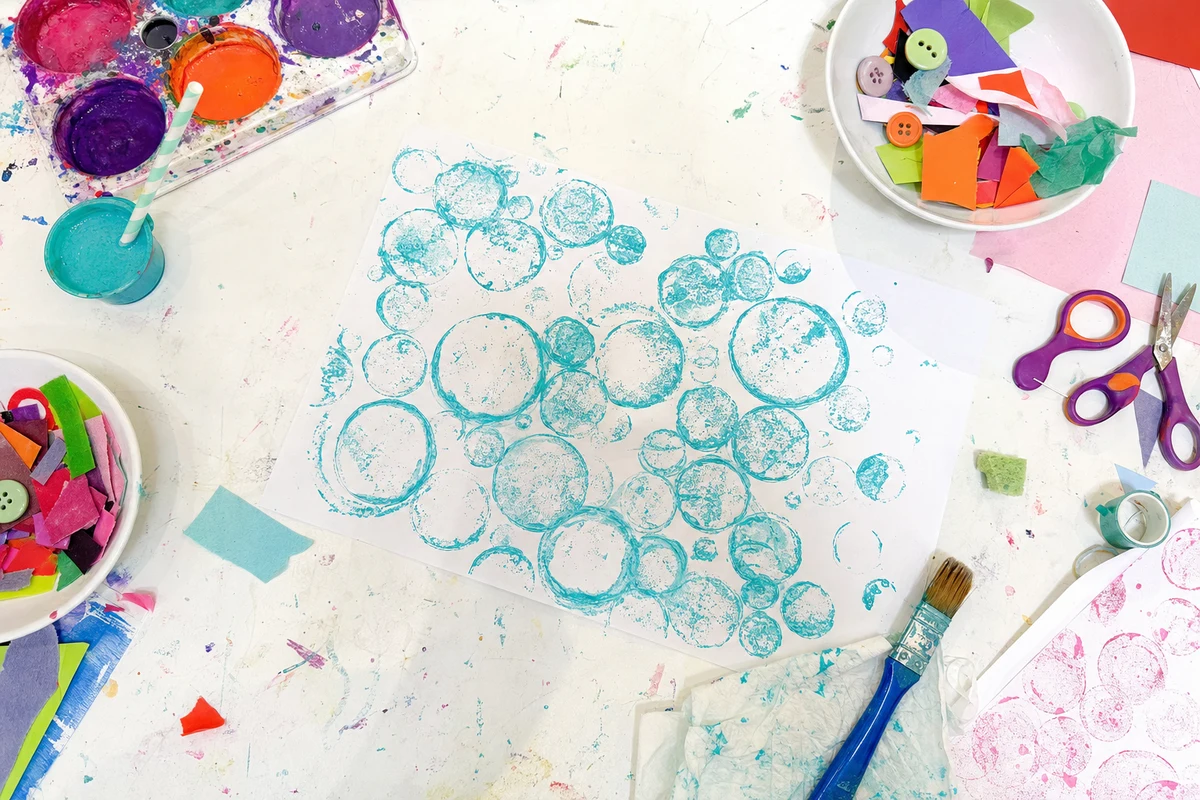 Clusters of printed bubble circles on paper beside a cup and straw