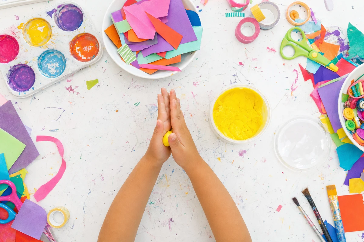 Two hands warming a ball of playdough between flat palms on a mat