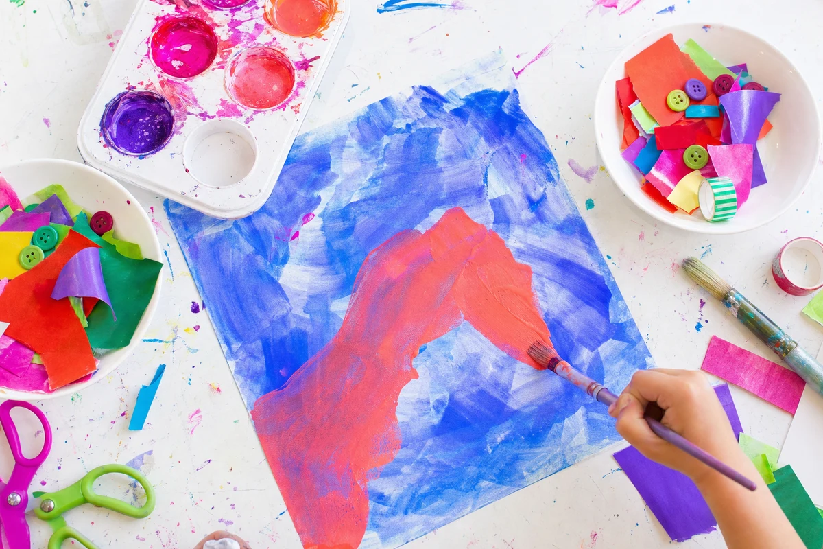 A hand painting a warm coral shape on top of a dried cool background